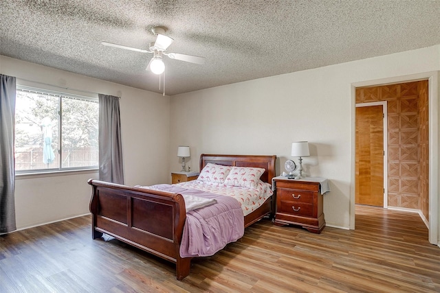 bedroom featuring ceiling fan, hardwood / wood-style floors, and a textured ceiling