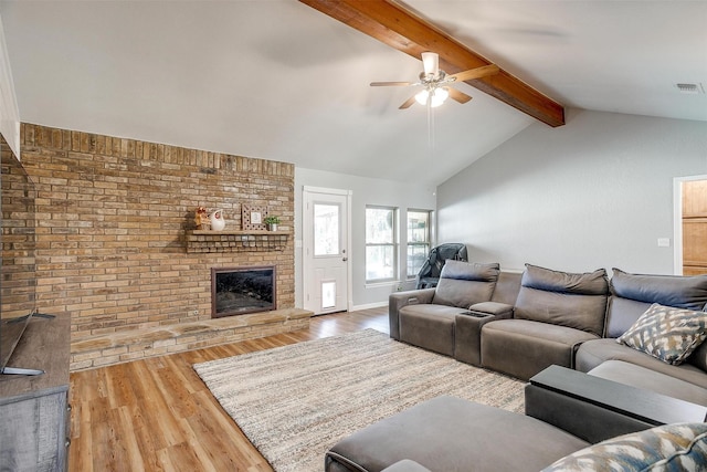 living room with ceiling fan, hardwood / wood-style flooring, lofted ceiling with beams, and a brick fireplace