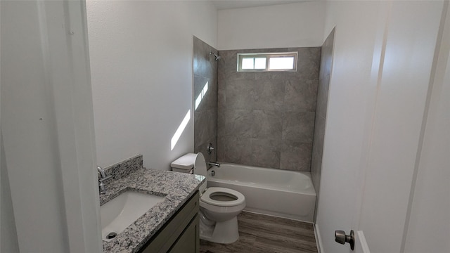 full bathroom with hardwood / wood-style floors, tiled shower / bath combo, vanity, and toilet