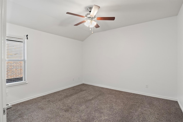 spare room featuring ceiling fan, dark carpet, a wealth of natural light, and lofted ceiling