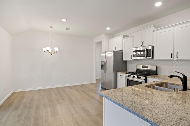 kitchen with white cabinets, appliances with stainless steel finishes, sink, and vaulted ceiling