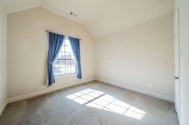 empty room featuring light carpet and vaulted ceiling