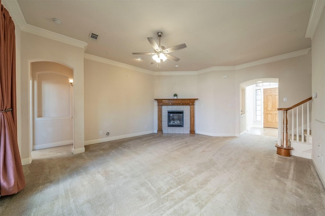 unfurnished living room with crown molding, light colored carpet, a fireplace, and ceiling fan