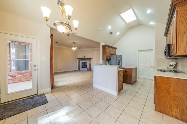 kitchen with decorative light fixtures, black appliances, vaulted ceiling, light tile patterned floors, and backsplash