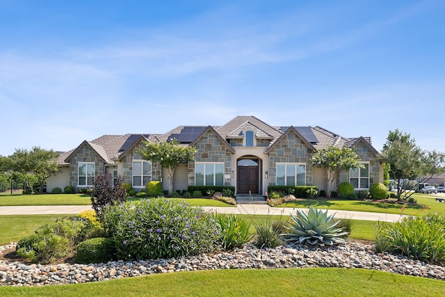 view of front of home with a front yard and solar panels