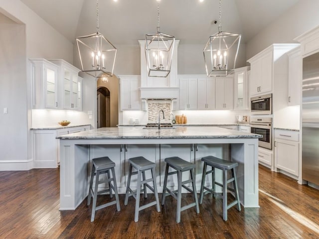 kitchen with stainless steel appliances, white cabinetry, decorative backsplash, and a spacious island