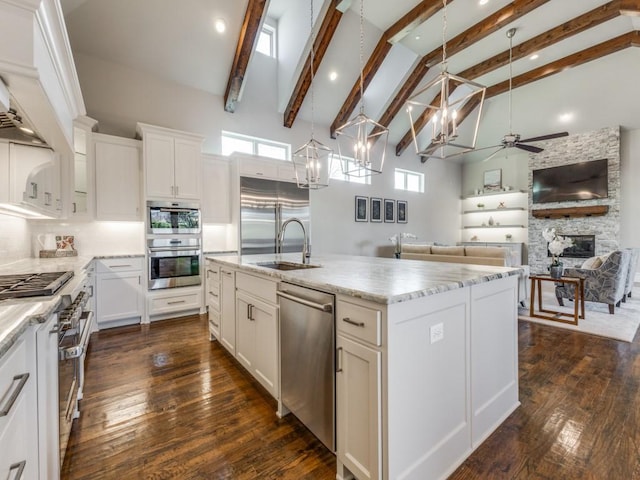 kitchen featuring hanging light fixtures, appliances with stainless steel finishes, sink, high vaulted ceiling, and a center island with sink