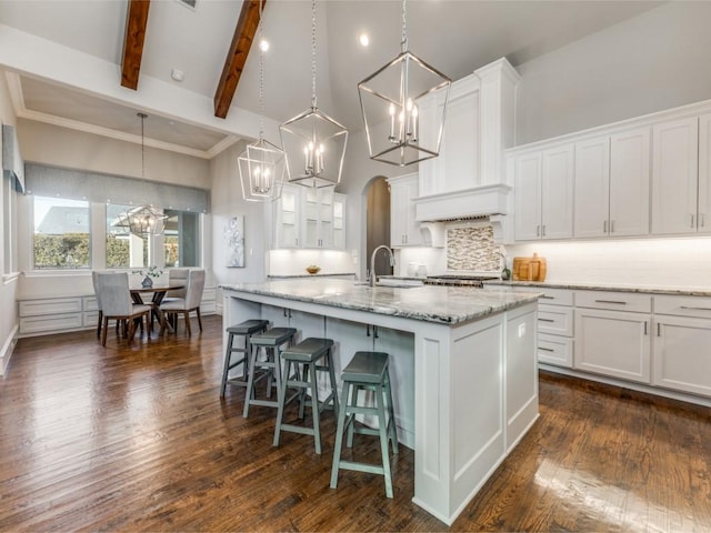 kitchen with pendant lighting, white cabinets, a kitchen island with sink, and a chandelier