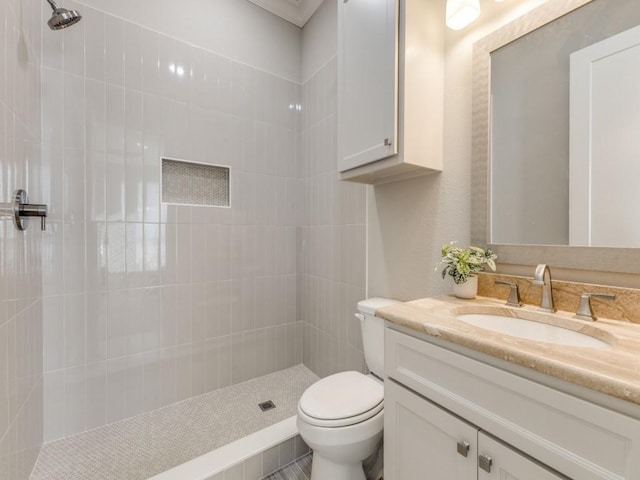 bathroom with vanity, toilet, and tiled shower