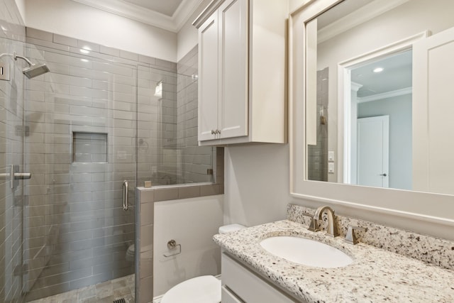 bathroom featuring toilet, a shower with shower door, vanity, and ornamental molding