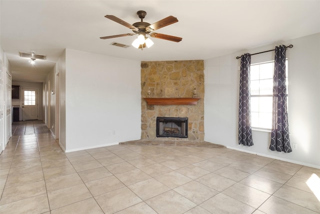 unfurnished living room featuring ceiling fan, a stone fireplace, and light tile patterned flooring