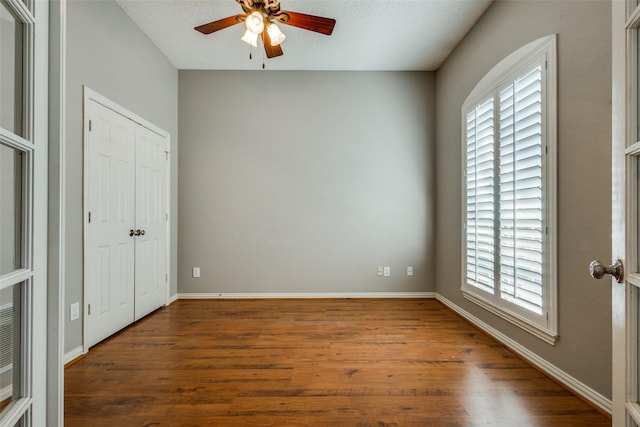 unfurnished bedroom featuring ceiling fan, dark wood-type flooring, and a textured ceiling