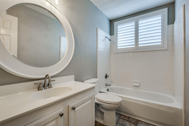 full bathroom with vanity, toilet, a textured ceiling, and tiled shower / bath combo