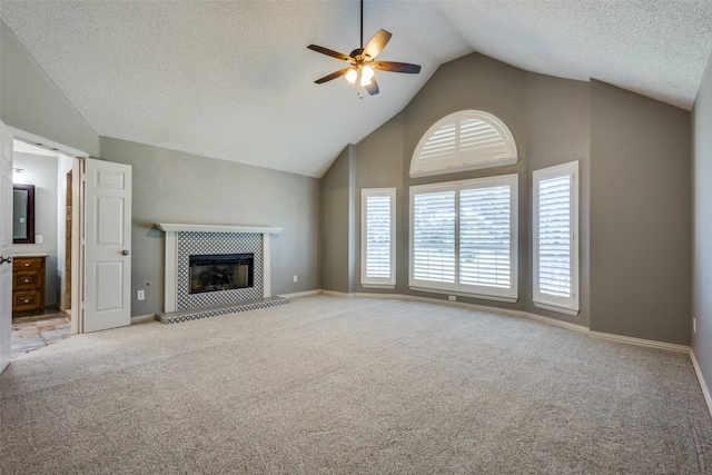 unfurnished living room with a textured ceiling, light carpet, a fireplace, vaulted ceiling, and ceiling fan