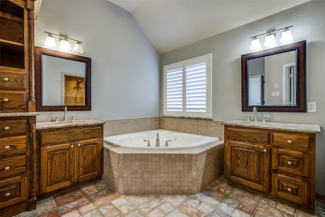 bathroom with vanity, vaulted ceiling, and a relaxing tiled tub