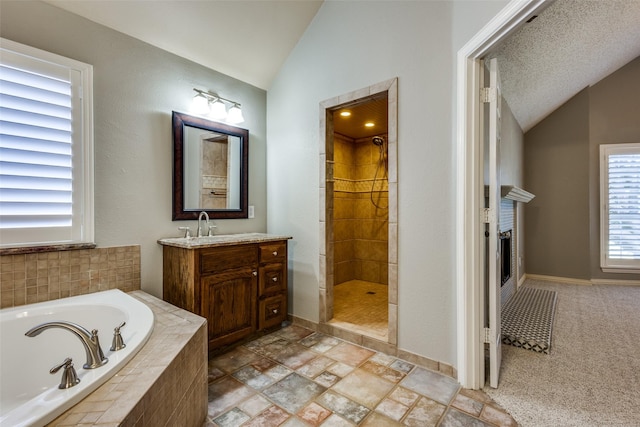 bathroom with a textured ceiling, vanity, lofted ceiling, and separate shower and tub