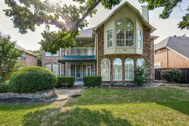 rear view of property with a balcony, a yard, and ceiling fan