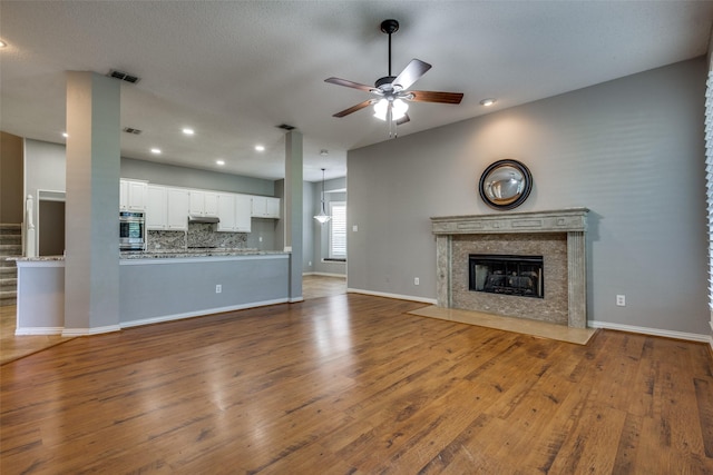 unfurnished living room featuring hardwood / wood-style floors, ceiling fan, and a premium fireplace