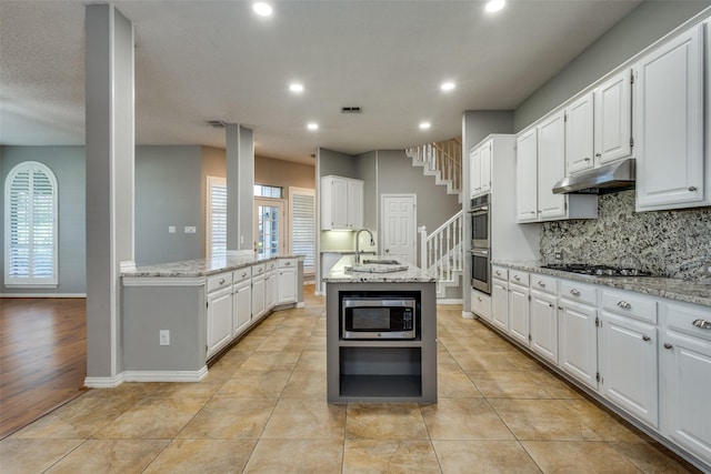 kitchen with white cabinets, appliances with stainless steel finishes, and an island with sink