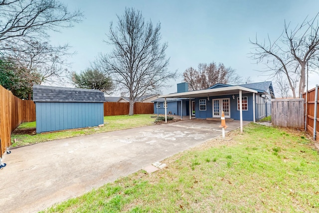 1721 Melrose St, Garland, TX 75042 - rear view of house featuring concrete driveway, a storage unit, french doors, an attached carport, and a fenced backyard