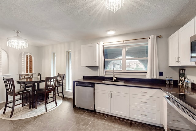 1721 Melrose St, Garland, TX 75042 - kitchen featuring stainless steel appliances, a chandelier, dark countertops, a textured ceiling, and white cabinetry