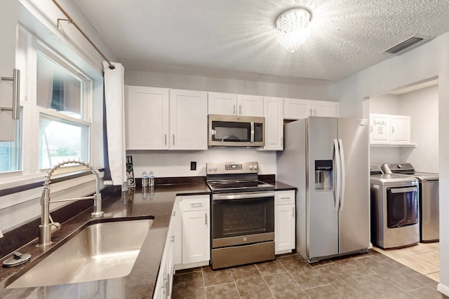 1721 Melrose St, Garland, TX 75042 - kitchen featuring dark countertops, visible vents, a sink, stainless steel appliances, and separate washer and dryer