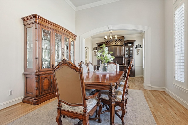 dining space with an inviting chandelier, ornamental molding, light hardwood / wood-style floors, and plenty of natural light