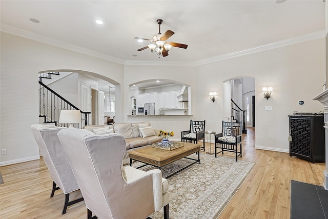 living room featuring crown molding, ceiling fan, and light hardwood / wood-style flooring