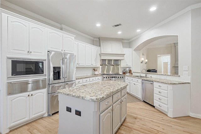 kitchen with sink, white cabinets, premium appliances, kitchen peninsula, and custom range hood