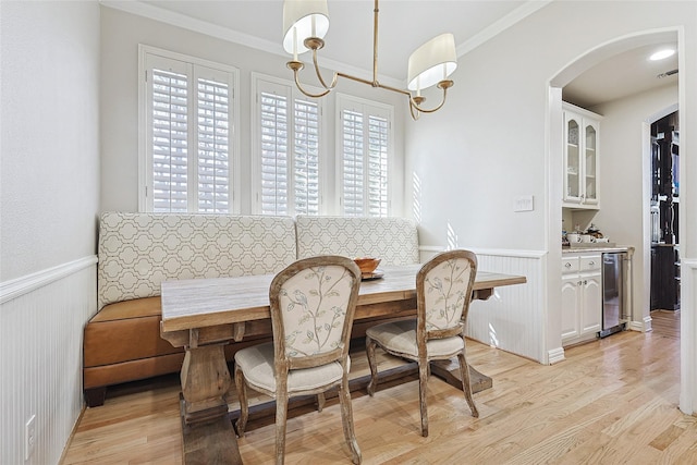 dining area featuring breakfast area, crown molding, wine cooler, and light wood-type flooring