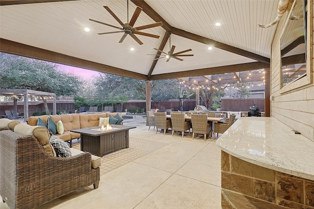 patio terrace at dusk with an outdoor living space with a fire pit, an outdoor bar, and ceiling fan