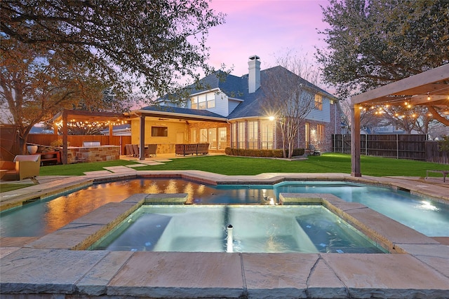 pool at dusk featuring a lawn and an in ground hot tub