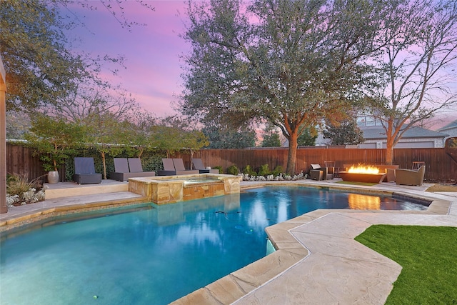 pool at dusk featuring an in ground hot tub, a patio, and an outdoor fire pit