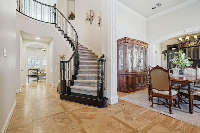 foyer entrance featuring light parquet floors, crown molding, and a towering ceiling