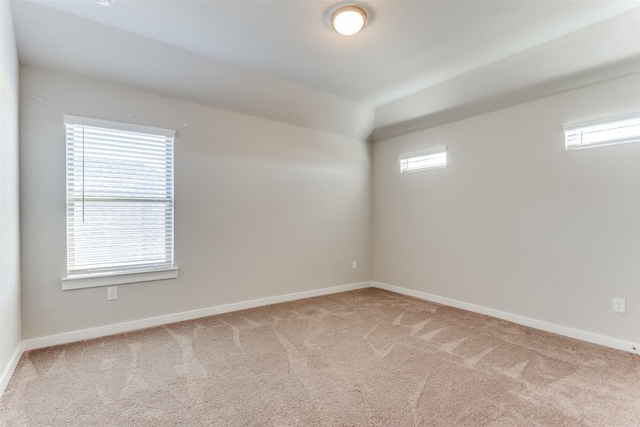 empty room featuring light colored carpet, lofted ceiling, and a wealth of natural light