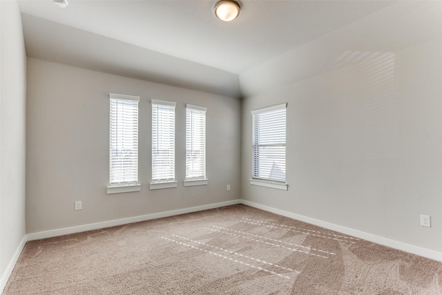 carpeted empty room featuring lofted ceiling and plenty of natural light