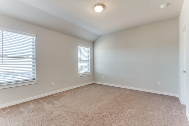 spare room featuring lofted ceiling, a wealth of natural light, and carpet