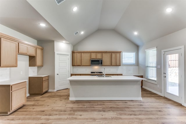 kitchen with sink, light hardwood / wood-style floors, an island with sink, and high vaulted ceiling