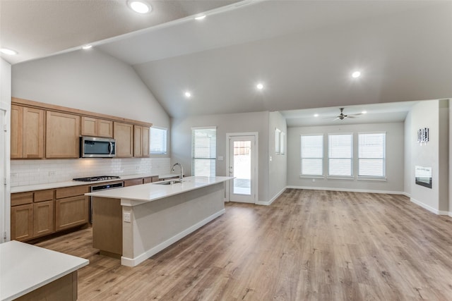 kitchen with sink, decorative backsplash, a kitchen island with sink, stainless steel appliances, and light wood-type flooring