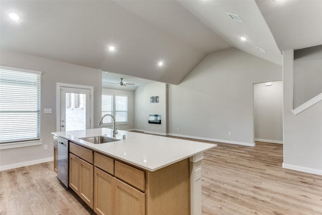 kitchen with sink, dishwasher, a center island with sink, vaulted ceiling, and light wood-type flooring