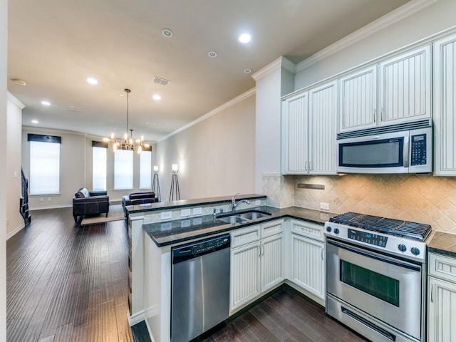 kitchen featuring appliances with stainless steel finishes, white cabinetry, a chandelier, sink, and kitchen peninsula