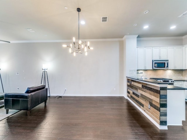 kitchen with crown molding, hanging light fixtures, dark hardwood / wood-style flooring, white cabinetry, and decorative backsplash