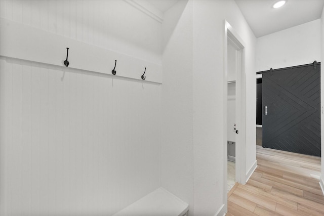 mudroom with a barn door and light wood-type flooring