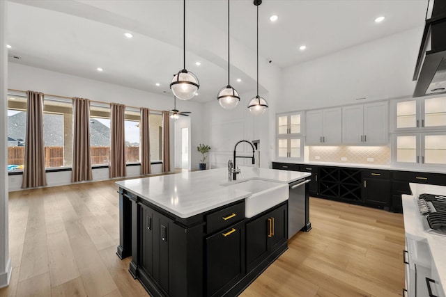 kitchen with pendant lighting, sink, white cabinets, stainless steel dishwasher, and a center island with sink