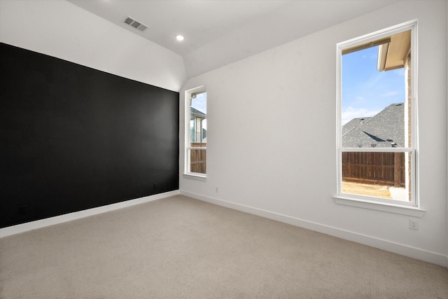 spare room featuring light carpet and vaulted ceiling