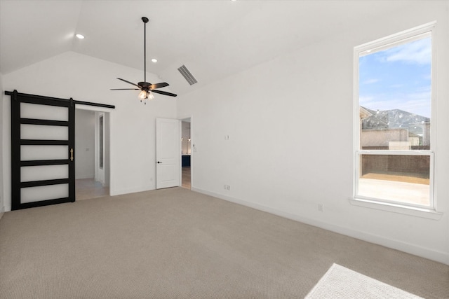 unfurnished bedroom featuring lofted ceiling, a barn door, a mountain view, and multiple windows