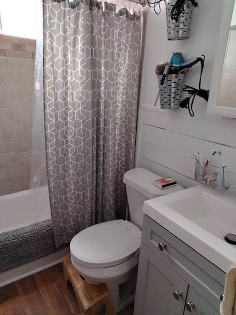 full bathroom with hardwood / wood-style flooring, vanity, shower / bathtub combination with curtain, and toilet