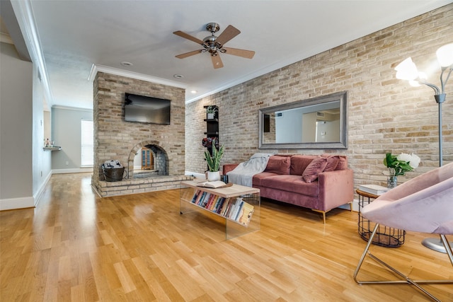 living room with crown molding, hardwood / wood-style flooring, ceiling fan, a fireplace, and brick wall