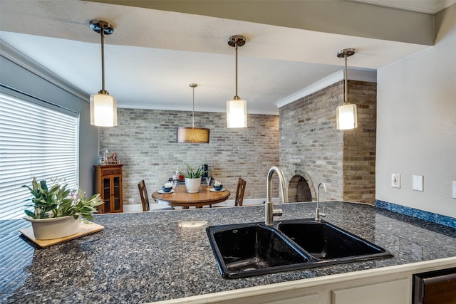 kitchen featuring ornamental molding, brick wall, sink, and pendant lighting