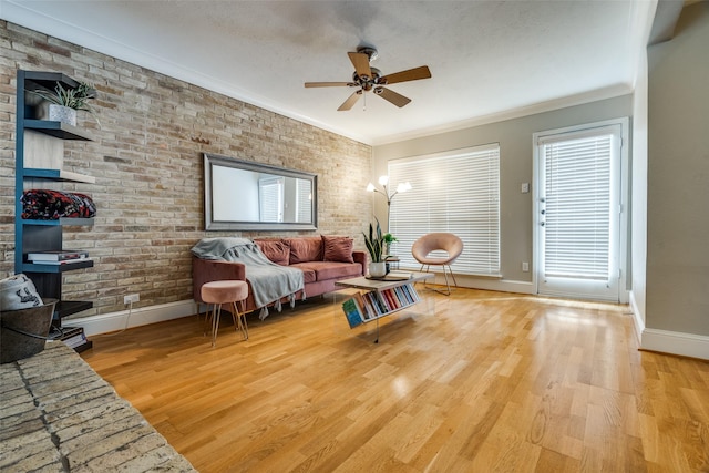 living room featuring light hardwood / wood-style flooring, ornamental molding, a textured ceiling, and brick wall